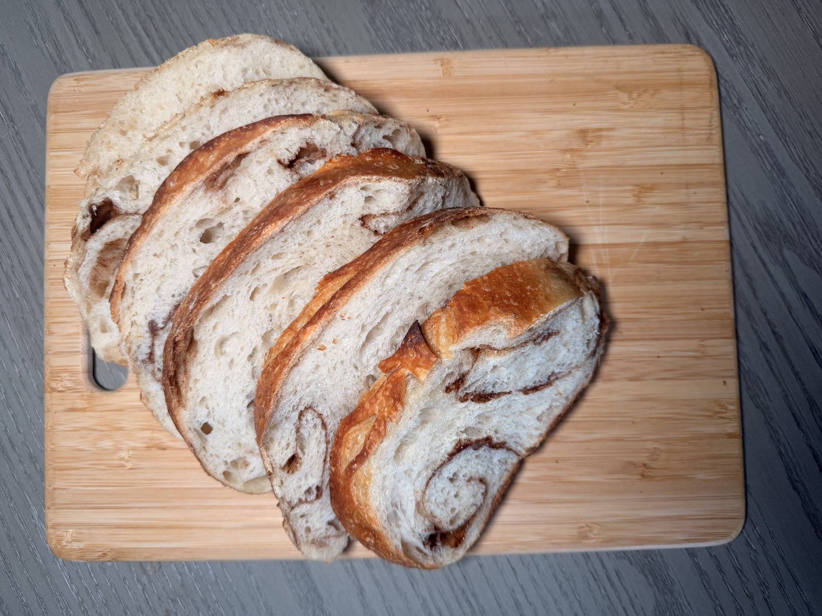 Cinnamon swirl sourdough slices on a wooden cutting board
