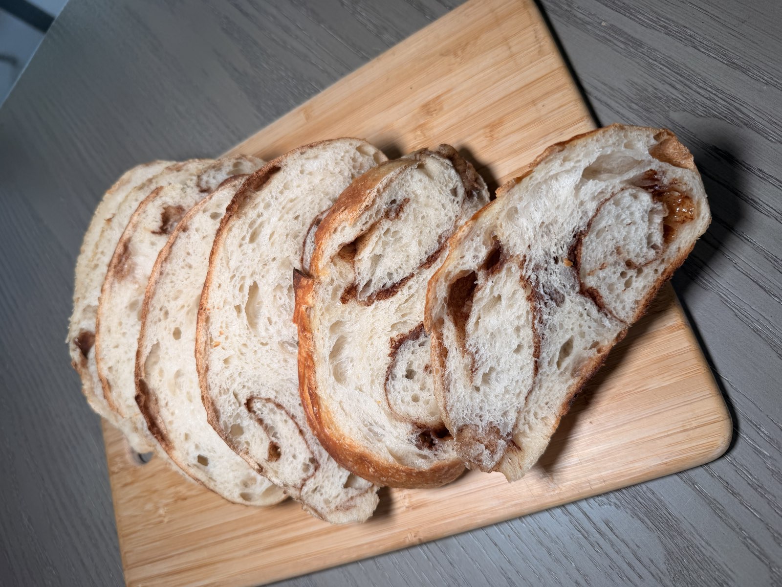 Cinnamon swirl sourdough slices fanned on a wooden board
